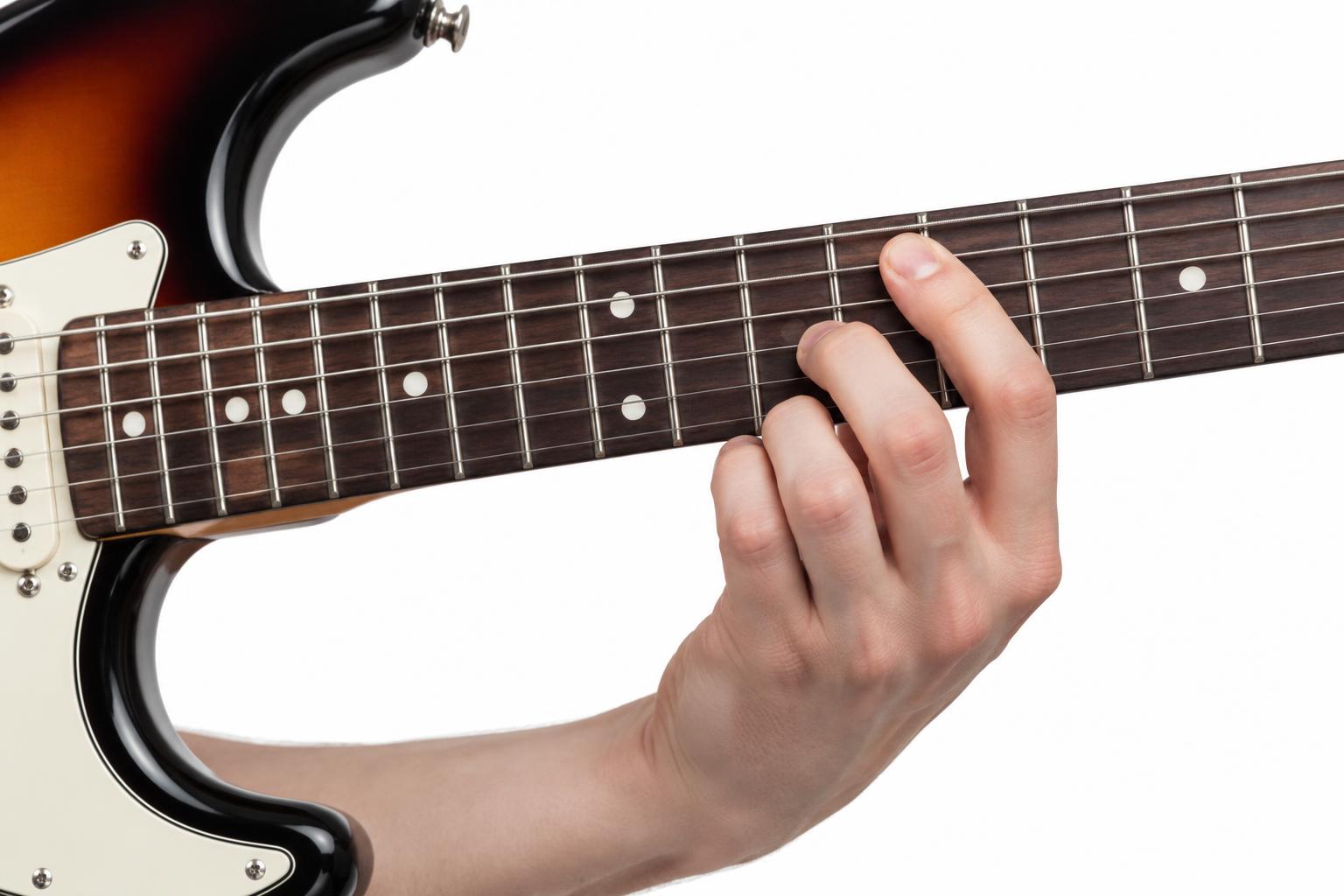 A hand forming a chord on an electric guitar